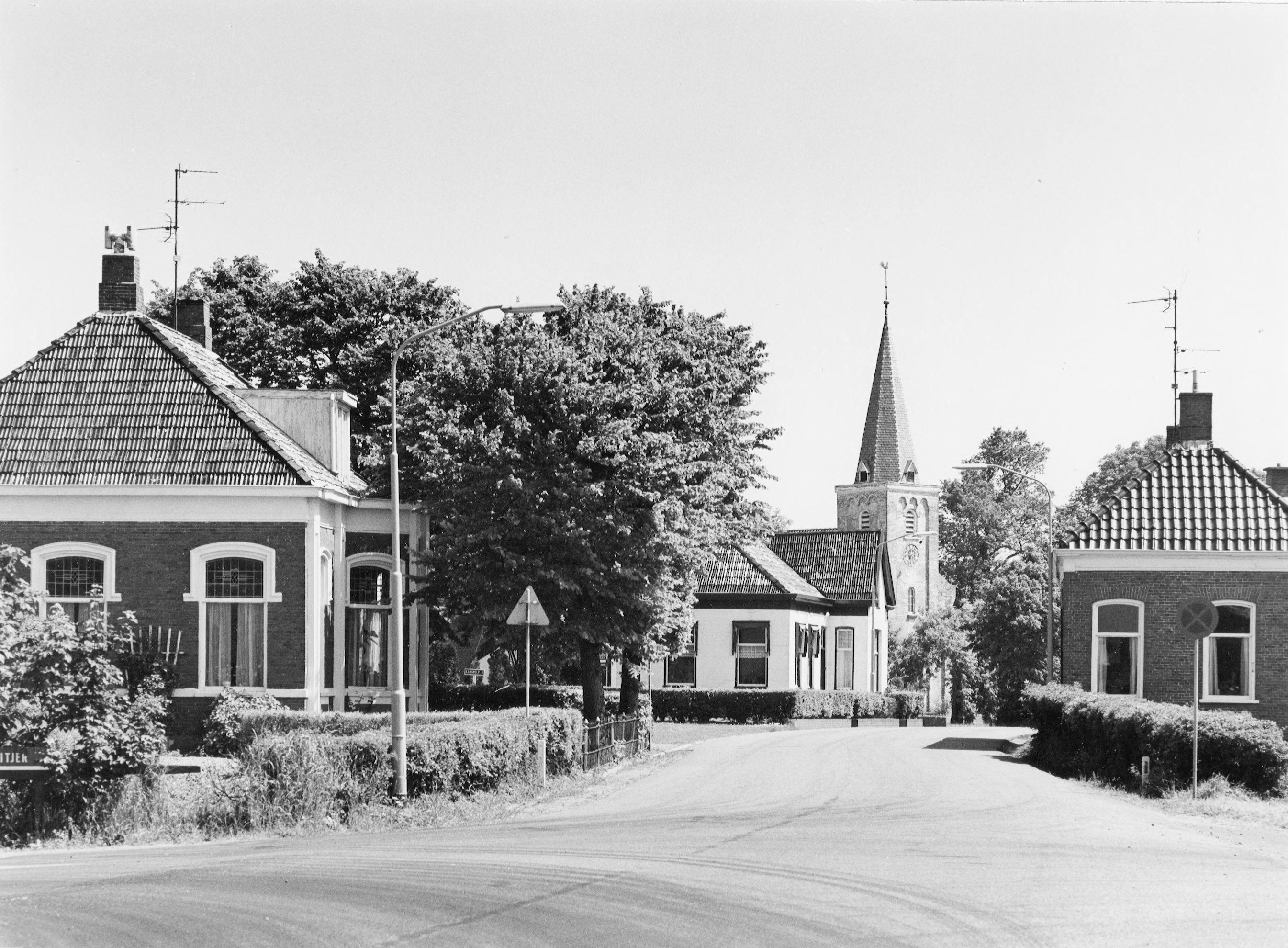 Hoofdweg Weiwerd. Dorpsgezicht naar het oosten, ter hoogte van de Westerlaan. Café is gebouw 2e van links. Kerktoren in het midden. Vervaardiger: M.A. Douma. Bron: RHC GA, Groninger Archieven, Beeldbank Groningen.