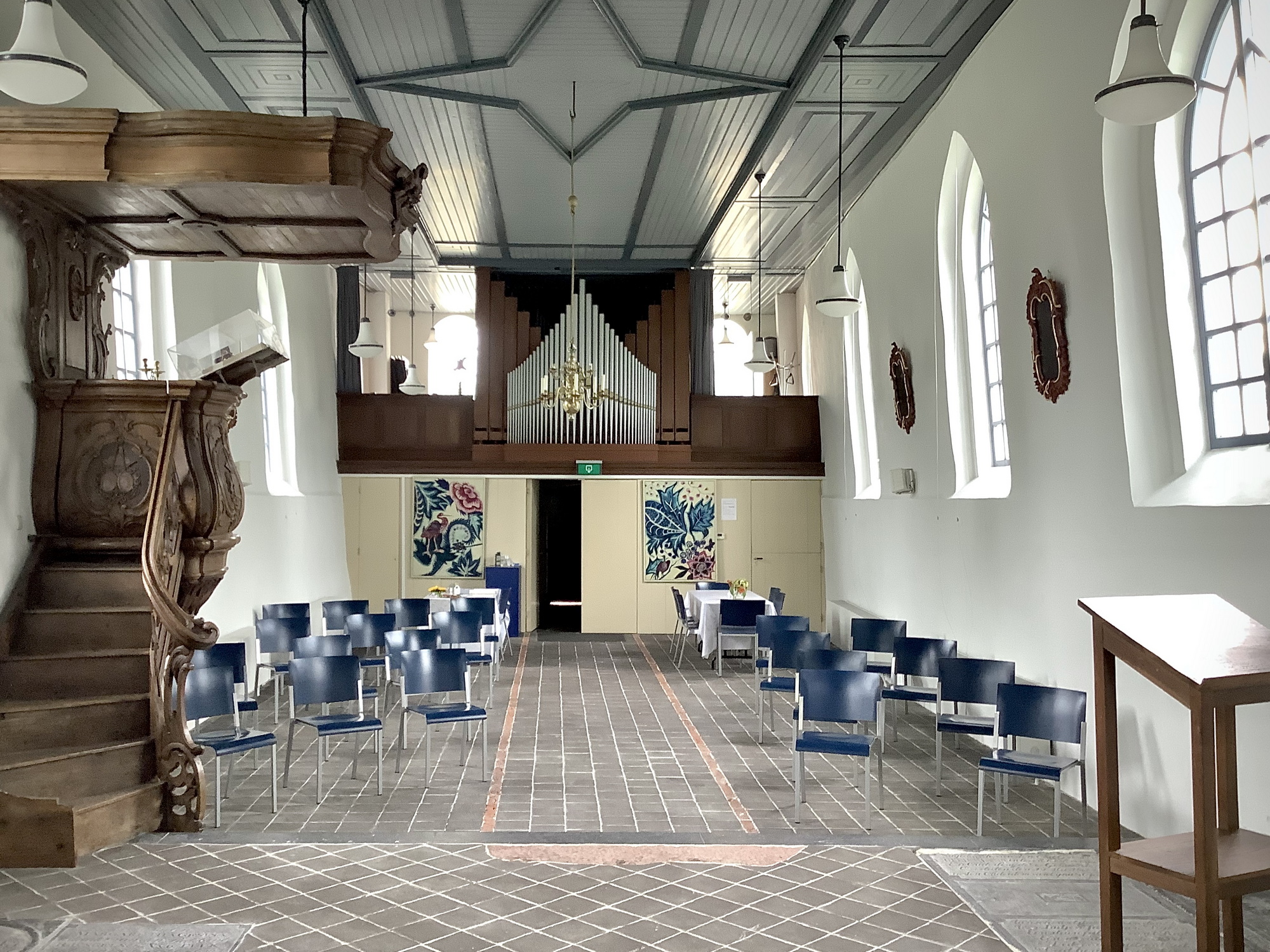 Het huidige interieur gezien naar het westen gezien vanaf het koor. Links de preekstoel uit de kerk van Heveskes en rechts aan de muur twee borden uit de kerk van Oterdum. Foto: ©Jur Kuipers.