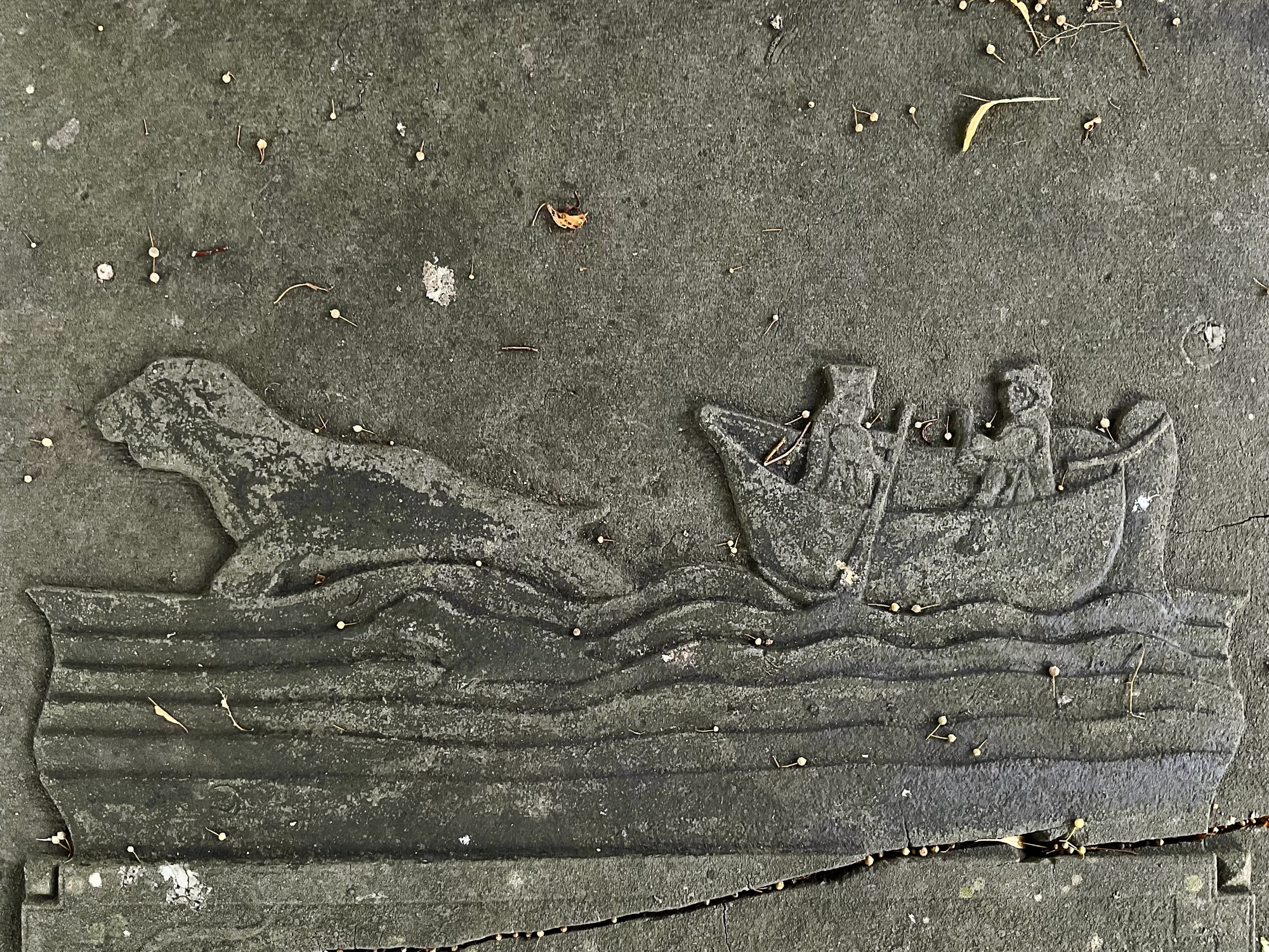 Abeelding op de zerk toont een boot met 2 mannen, een roeier en een stuurman, die duidelijk de jacht hebben geopend op twee zeehonden. Foto: ©Jur Kuipers.