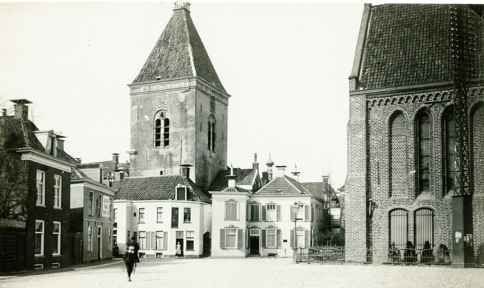 Marktplein met rechts de Ned. Herv. Kerk gezien vanuit het zuidoosten en in het miden d'Olle Witte, de kerkpleinkerk van Winschoten. Foto gemaakt tussen 1900 en 1915. Bron: RHC GA, Groninger Archieven, Beeldbank Groningen