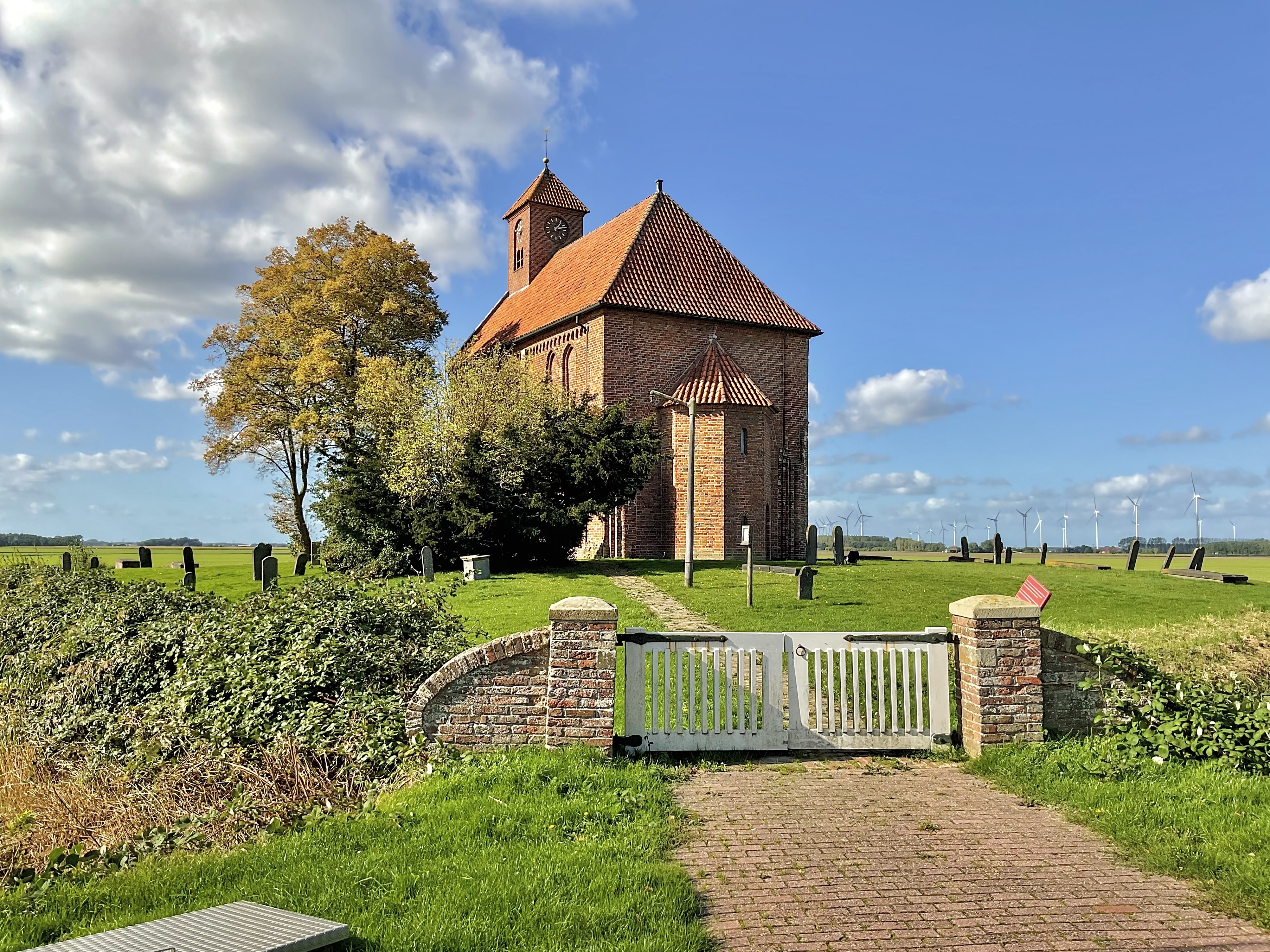 De kerk gelegen op de wierde met het oude kerkhof.