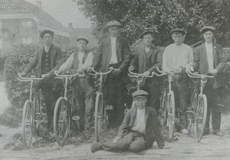 Een foto met 7 dorpsvrienden, waarvan een drietal broers Van der Laan. Wat hierbij opvalt zijn de carbidlantaarns op hun fietsen en dat iedereen een pet draagt. De foto is genomen bij het huis van de ouders van Loete in Borgsweer. Helemaal links Loete van der Laan, derde van links Evert van der Laan met vooraan op de grond Reintjo die schijnbaar geen fiets heeft.